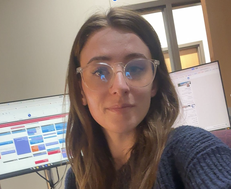 Tessa Hill authentic office photo, not AI. authentic photo in regular office with everyday items like blanket, monitor, and notepad. cropped to face